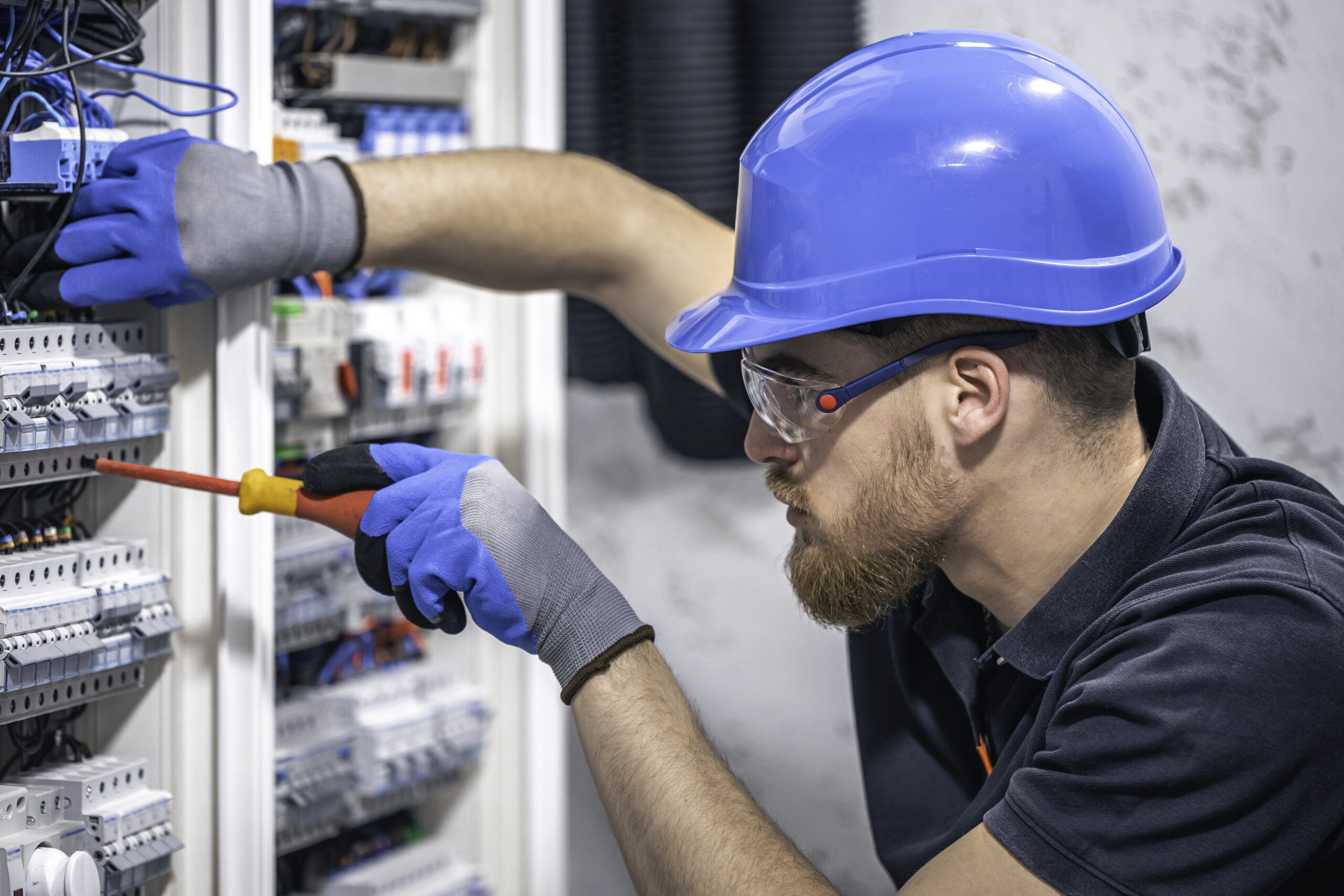 male electrician works switchboard with electrical connecting cable